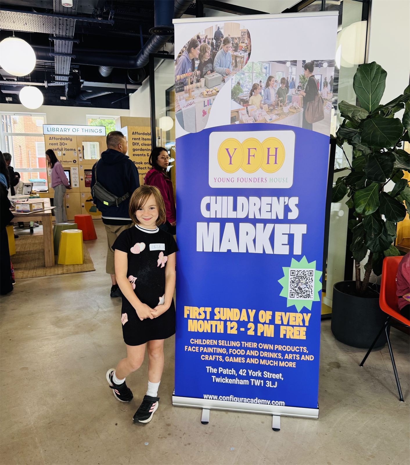 A child beside the Young Founders House children's market banner